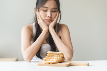 Gluten allergy, asian young woman, girl refusing to eat, looking at bread slice on plate in...