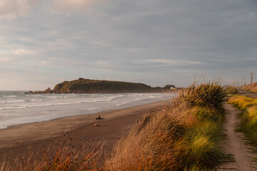 View of beautiful sunset on the shore of Cape Foulwind with beach views and rolling dark clouds (Cape Foulwind, South Island, New Zealand)