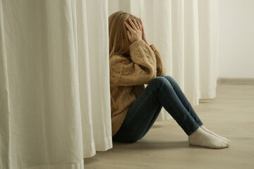 Sad and lonely little girl sitting on the floor at home, child looking for parental attention