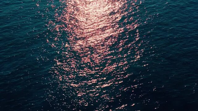 Bright sunset sun reflecting on blue surface of Caribbean Sea. Calm ripples of small waves. Vast blue ocean background with moderate waves, looking straight down. Tropical landscape. Tourism.