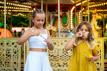 children in the amusement park and attractions, happy children inflate soap bubbles and enjoy the...