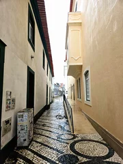 Fotobehang a narrow alley among houses on European streets  © Liza