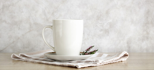 White mug sitting on striped napkin with small purple flower