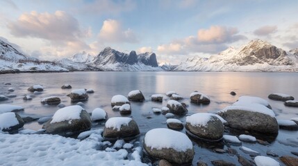 Obraz premium Scenic winter landscape with snow-covered rocks by calm lake and mountain range at sunset.