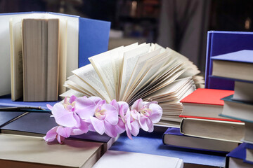 stack of books with orchid, close up. Open book on the table in library. Back to school concept....