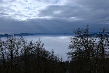 Hills rising above the fog and clouds in the sky in Slovenia