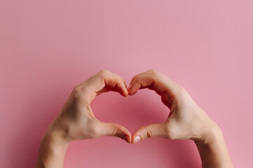 Obraz premium Female hands showing heart shape isolated on pink background. Sign of love, harmony, gratitude, charity. Feelings and emotions concep