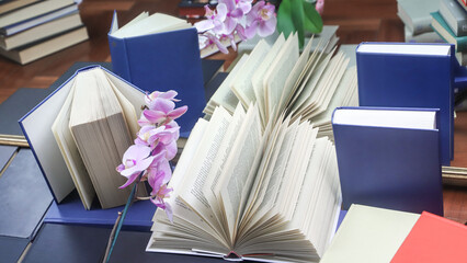 stack of books with orchid, close up. Open book on the table in library. Back to school concept....
