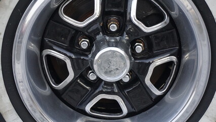 Detailed view of a shiny chrome wheel rim from a classic car, reflecting vintage design.