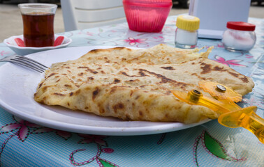 Delicious Turkish flatbread, as known Gözleme, served with a glass of tea, capturing the essence of local cuisine.