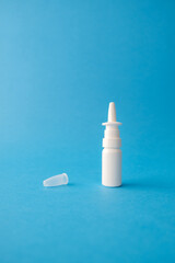 White bottle with the lid removed on a blue plain background with space for text