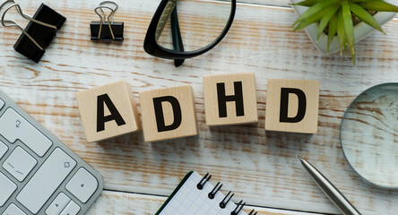 Wooden cubes with the word ADHD on a wooden background and a stethoscope on them. Medical concept