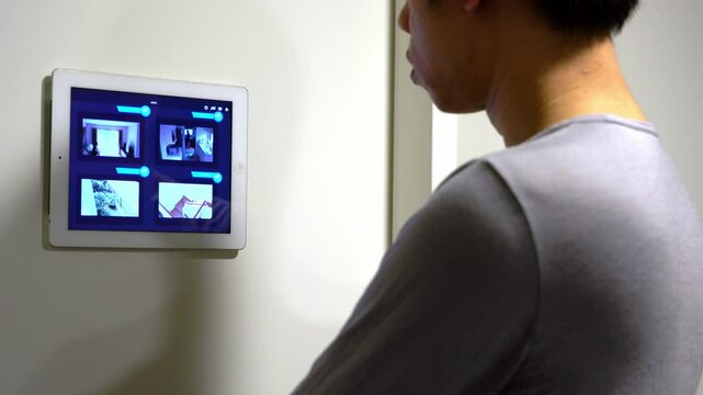 A person engages with a digital display mounted on a wall, showcasing multiple images or interfaces. This scene highlights the integration of technology in everyday environments.