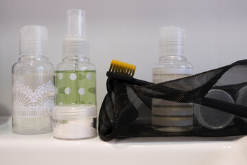 Filling a set of mini travel jars with cosmetics and care products in transparent bag