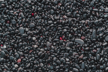 Black basalt pebbles and red clay stones on Víkurfjara Beach near Vík í Mýrdal, Iceland