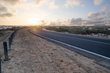 Beautiful morning on a road through the dunes. Sunrise over a road with clouds. Corralejo National...