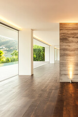 Elegant modern interior showcasing large windows and wooden flooring in bright natural light