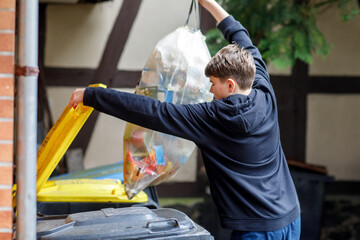 Teenage boy putting plastic waste into garbage bin. Teenager separates household waste.