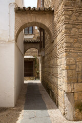 Empty alley between houses in Cordoba, Spain. Street in the old town with arches.