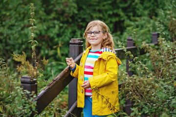Little preschool girl with eye glasses outdoors in park. Happy funny child on cloudy day on nature.