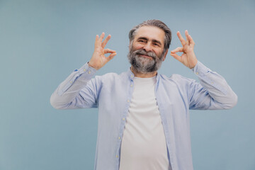 Smiling Senior Man Showing Ok Sign with Both Hands on Blue Background