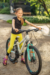 Naklejka premium Child enjoying sunny day while riding her bicycle in park