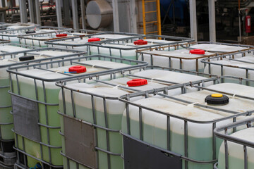 Stacked IBC totes, industrial chemical storage, outdoor setting - obrazy, fototapety, plakaty