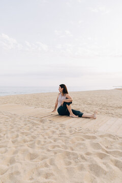Woman practicing Ardha Matsyendrasana yoga pose on beach