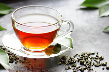 Green chinese tea with fresh leaves, hot drink on black background, closeup, natural medicine and naturopathy concept