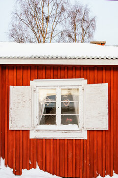 Fototapeta Traditional Swedish red cottage window with snow in winter
