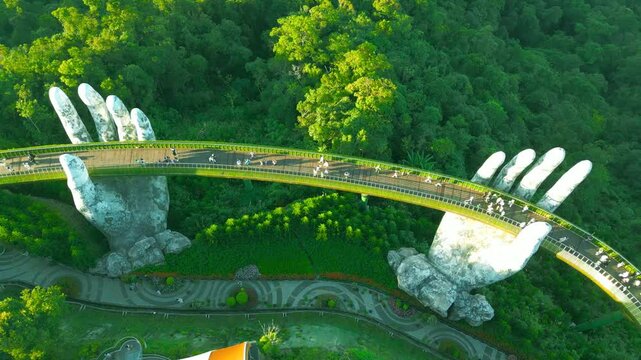 Aerial view of the Golden Bridge in Da Nang, Vietnam, featuring giant stone hands supporting a wooden walkway among lush greenery.