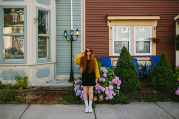 Fashionable woman posing in front of a colorful house in St. John's