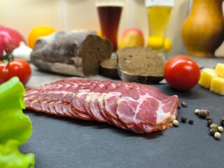 Thin slices of bacon lie on a sliced board in the background of a beer tank