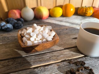 small pieces of marshmallows in a wooden plate next to a cup of coffee.