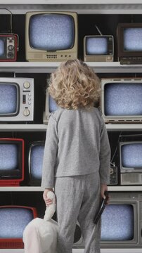 small girl watches a televisions wall with distortion on the screens in vertical