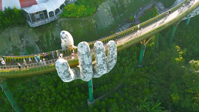 Aerial view of the Golden Bridge in Da Nang, Vietnam, showcasing its unique hand supports and bustling visitors amidst lush greenery.