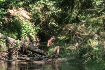 Beautiful young dark-haired girl in a forest river in summer.
