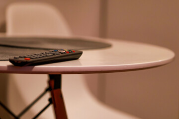 The TV remote control is forgotten on the white table.