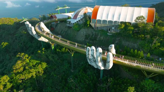 Aerial view of the Golden Bridge in Da Nang, Vietnam, showcasing its iconic giant hands and lush surrounding landscape.