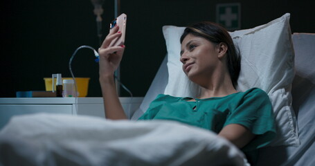 Hospitalized young woman with oxygen tube in her nose, engaged in a video chat.