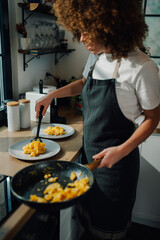 Woman chef serving scrambled eggs in restaurant kitchen