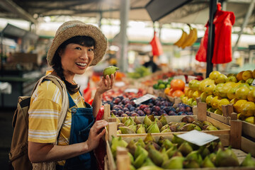 Asian woman in straw hat browsing fruits at local outdoor market