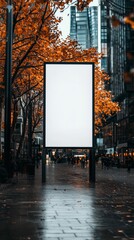 A large blank billboard is positioned in the middle of a vibrant city street with static camera. Surrounding trees display golden leaves as pedestrians stroll by during early evening.
