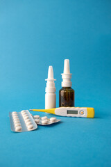 Two blisters with tablets, a white and brown bottles of nasal drops and a thermometer
