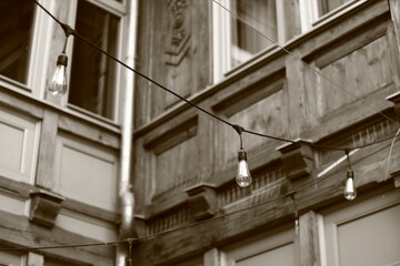 three classic electric bulbs hanging between the wooden walls of the building, black and white photo, sepia, Vintage String Lights on Wooden Building