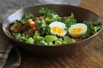 Vegan salad with kale, avocado, crispy bacon, egg and Vinaigrette dressing