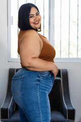 portrait of plus size brunette woman wearing jeans standing in profile at home, chubby model