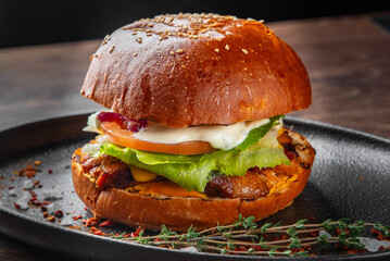 A delicious burger stacked with juicy meat, fresh lettuce, tomato, and creamy sauce, all nestled in a golden sesame seed bun. Perfect for food lovers and culinary presentations.