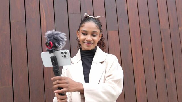 Content creator recording a vlog in slow motion using a smartphone and external microphone with a furry windscreen