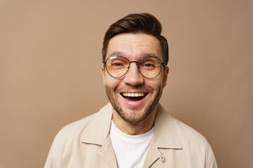 Man with glasses smiles brightly against a plain background during daytime smiling joyfully